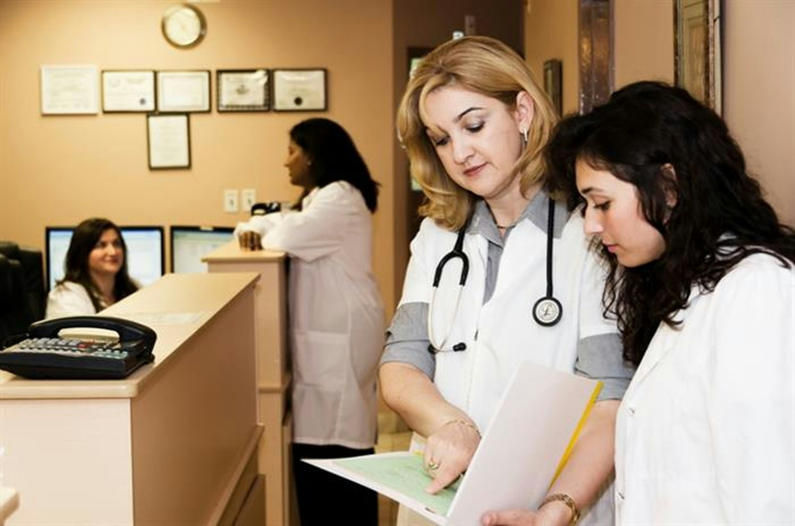 Clinic staff reviewing a patient file at a reception desk, a service example of Lean Six Sigma service vs manufacturing