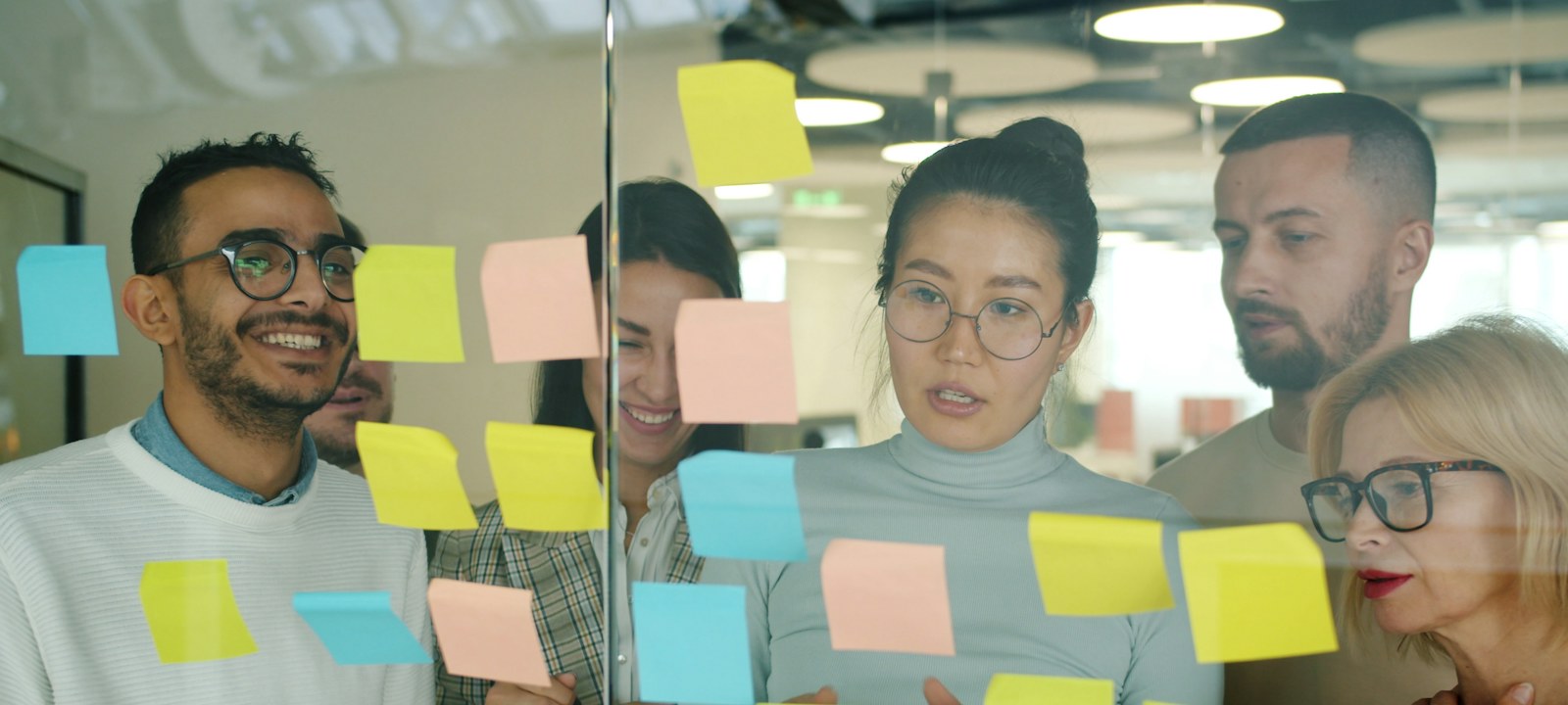 Team mapping a service process with sticky notes on a glass wall to apply Lean Six Sigma in service businesses