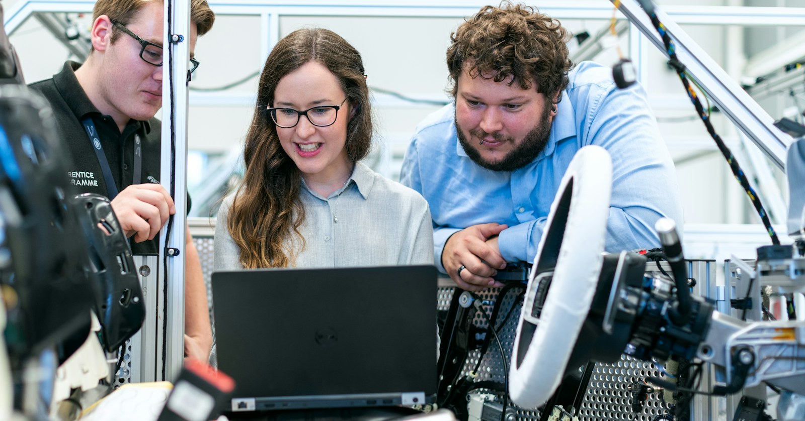Manufacturing team reviewing data together on a laptop beside automotive test equipment