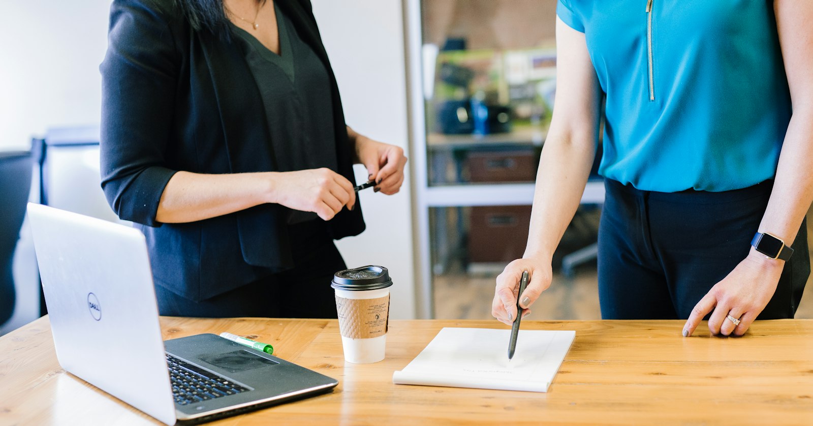 Employer reviewing an Ontario Job Grant training plan with a colleague at a desk beside a laptop