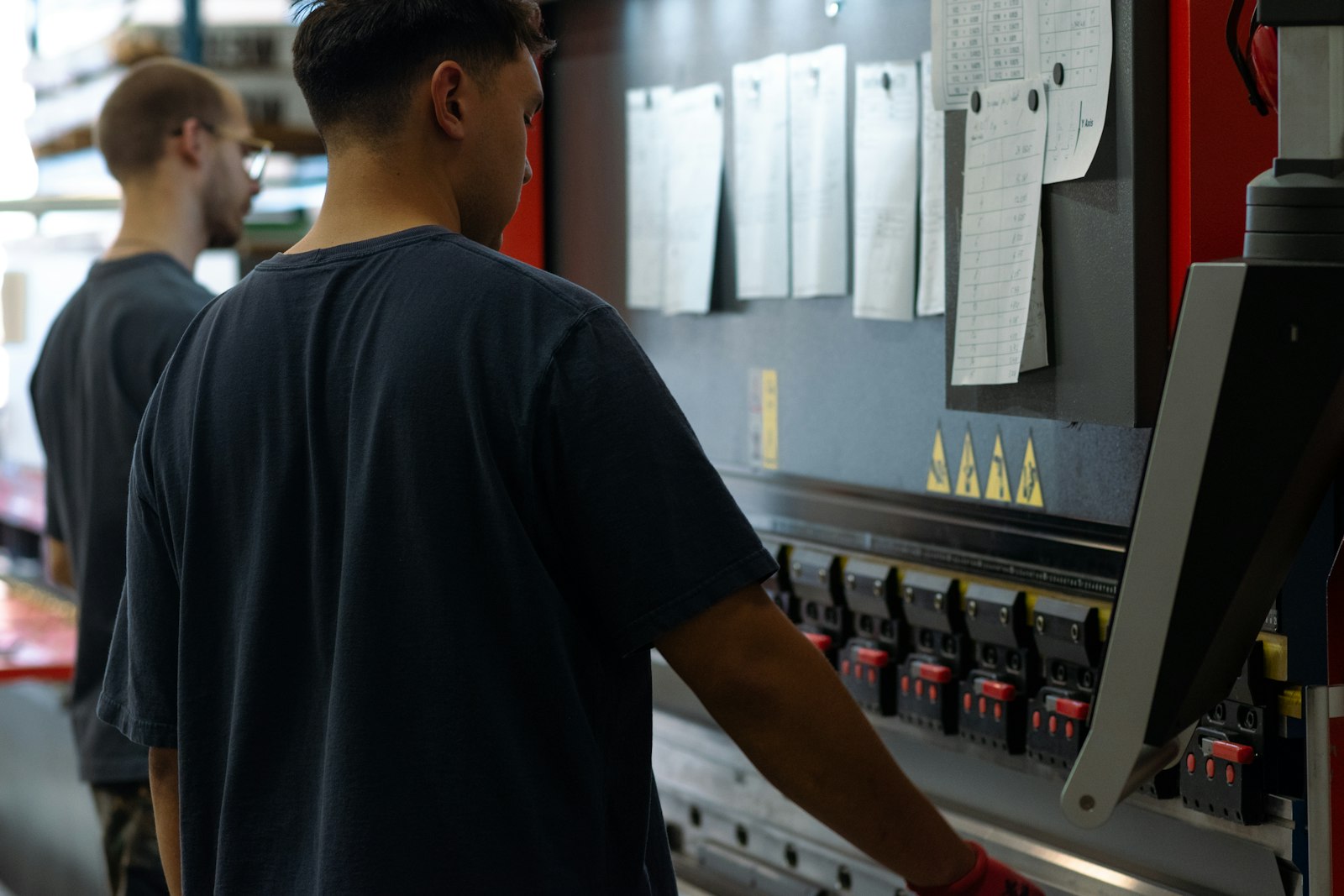 Supervisor training in practice: an operator runs a press brake while a lead hand checks the setup